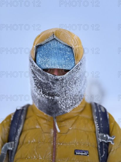 Young man wearing thick winter clothes, down jacket and scarf, with frozen snow in cold weather, Pallas-Yllästunturi National Park, Lapland, Finland