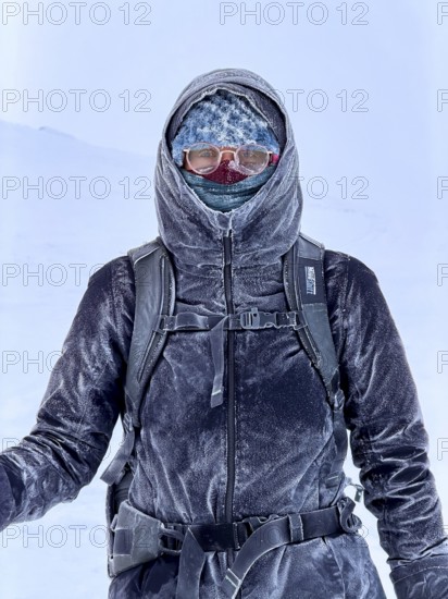 Young woman wearing thick winter clothes, down jacket and scarf, with frozen snow in cold weather, Pallas-Yllästunturi National Park, Lapland, Finland