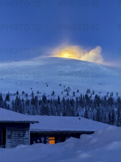 Snow sweeps over the fells in front of the moon at twilight, Hotel Pallas, Pallas-Yllästunturi National Park, Lapland, Finland
