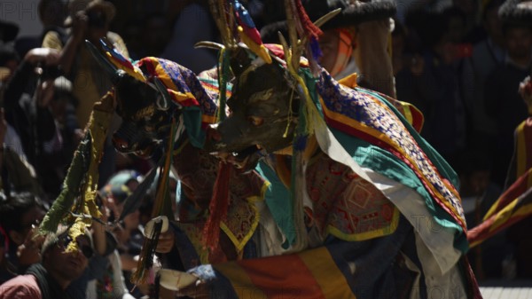 People wearing colorful masks and costumes conduct an outdoor ceremony, traditional cultural festival in Leh, trekking in Ladakh, Himalayas, India