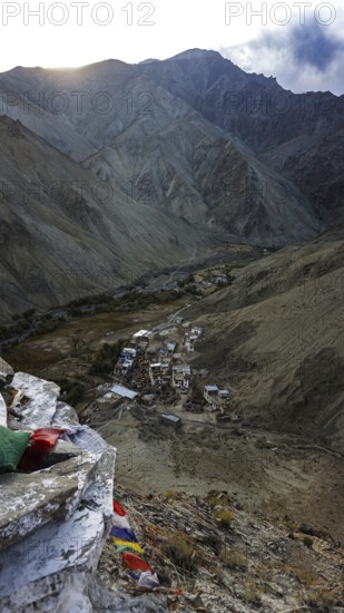 A small village surrounded by mountains in a remote valley under cloudy skies, trekking in Ladakh, Stok la, Himalayas, India