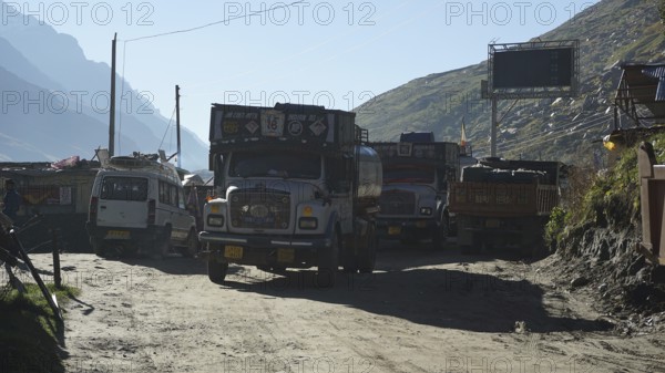 Several trucks on a mountain road in a small village in sunny weather on the Manali-Leh Highway, Leh, trekking in Ladakh, Himalayas, India