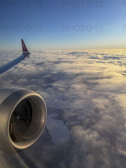 Airplane wing over sea of clouds in morning light, aerial view, Finland