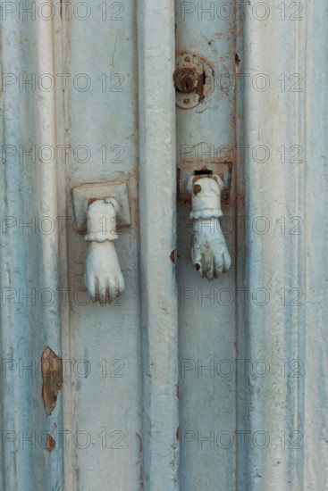 Old decorative hand shaped door knockers on a traditional blue painted door on an house in the Tunisian Kasbah, typical of homes in North Africa and the Middle East