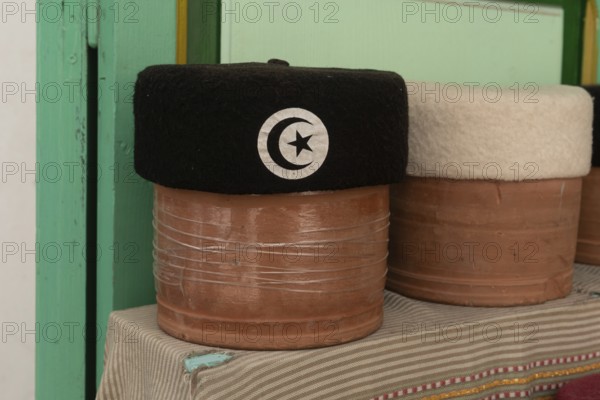 A black with crescent and star motif Tunisian Chechia, traditional soft wool hats popular in the Maghreb region of North Africa for sale in Souk Ech-Chaouachine, the Medina of Tunis, Tunisia