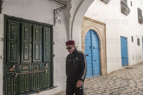 Tunis, Tunisia 4th May, 2024 A Tunisian man wearing a red chechia hat in the beautiful narrow streets of Tunis Medina, a World Heritage protected quarter of the Tunisian capital