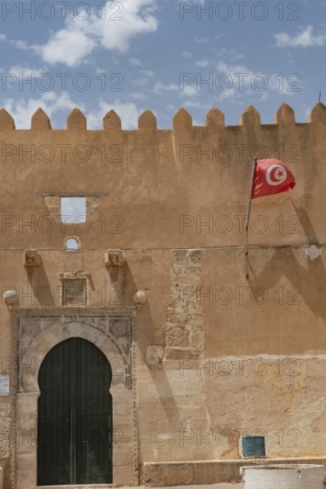 The Tunisian national flag flying from inside the ancient city walls of the medieval medina of Sfax on the Mediterranean coast of Tunisia, North Africa