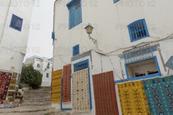 May 17th 2024. Sidi Bou Said, Tunisia. Tourist souvenir rugs hanging outside a store in the narrow streets of Sidi Bou Said, a pretty village near the Tunisian ruins of Carthage, Tunis, Tunisia