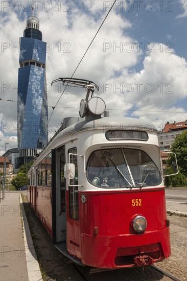 Sarajevo, Bosnia and Herzegovina July 25th 2019. An old tram waits at a tram stop with the Avaz Twist Tower in the background, Sarajevo, Bosnia and Herzegovina