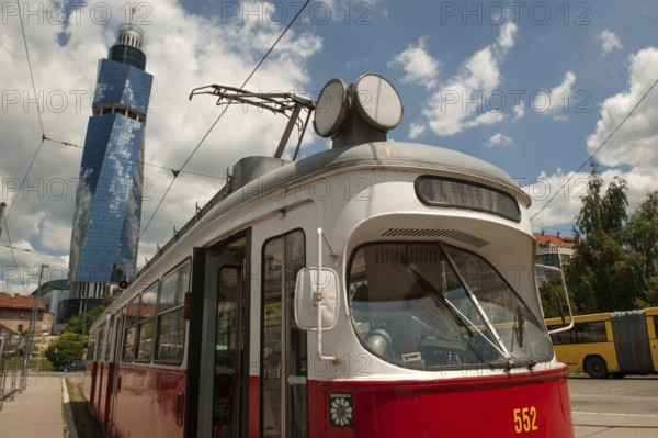 Sarajevo, Bosnia and Herzegovina July 25th 2019. An old tram waits at a tram stop with the Avaz Twist Tower in the background, Sarajevo, Bosnia and Herzegovina