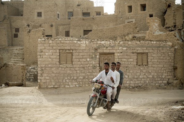 Siwa, Egypt. April 15th 2018. Three Egyptian men riding a motorcycle in the ruins of Shali fortress, Siwa, Egypt
