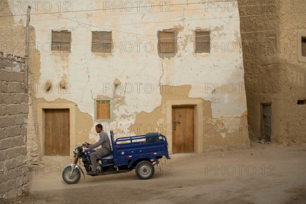 Siwa, Egypt, April 11th 2018 Motorcycle pick-up being driven through the mud brick houses of Siwa Oasis, Egypt