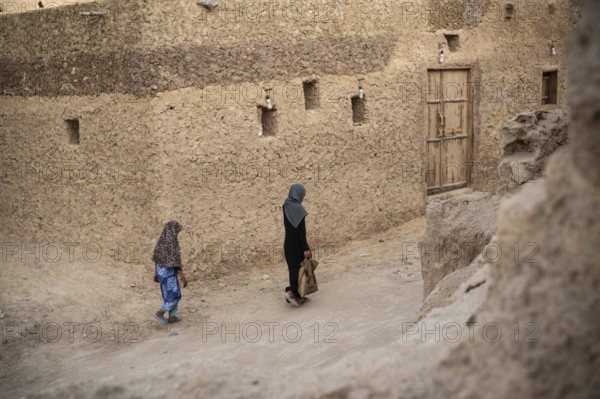 Siwa, Egypt. March 11th 2018 A woman and child walk through the traditional mud brick buildings of Siwa Oases
