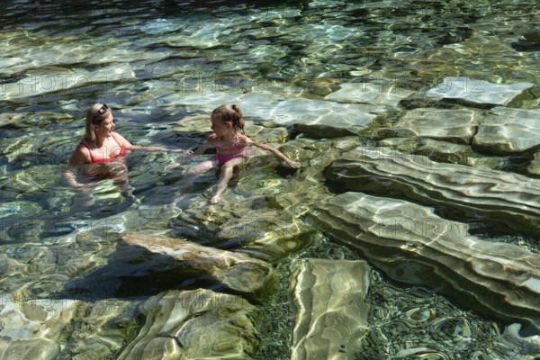 Pamakkale, Turkey, April 25th 2020 A woman and child enjoy the healing properties of thermal waters among fallen Roman columns in Cleopatra's Antique Pool in Pamakkale, Turkey