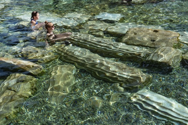 Pamukkale, Turkey, April 25th 2020 Foreign tourists enjoy the healing properties of thermal waters among fallen Roman columns in Cleopatra's Antique Pool in Pamukkale, Turkey Pamukkale, Turkey, April 25th 2020 The Turkish town of Pamukkale sitting at the base of the Travertine Terraces rock formation, a source of natural thermal spring water and world heritage site in western Turkey