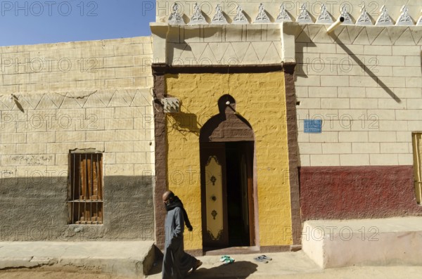 Aswan Egypt. January 10th 2013 Nubian Muslim man leaving a brightly coloured Mosque on Elephantine Island on the river Nile at Aswan Upper Egypt