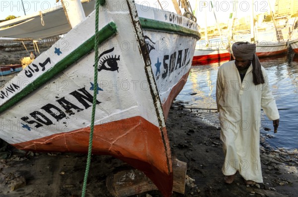 Aswan Egypt. January 12th 2013 Nubian Felucca captain with his sail boat on Elephantine Island beside the River Nile at Aswan Upper Egypt