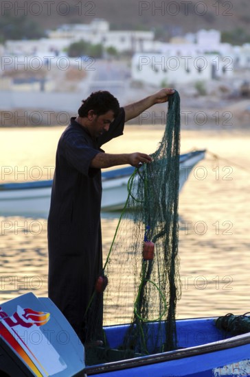 Tiwi, Oman. May 26th 2014. Silhouette of Omani fishermen at sunset in the fishing village of Tiwi on the coast of the Gulf of Oman