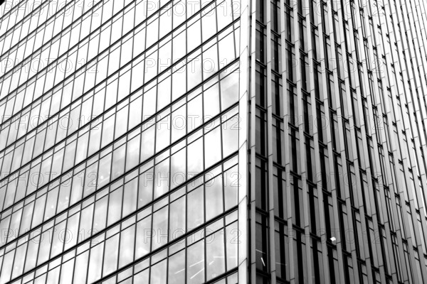 Modern black and white graphic image of abstract reflections in glass fronted commercial office buildings in the financial district of the British capital London