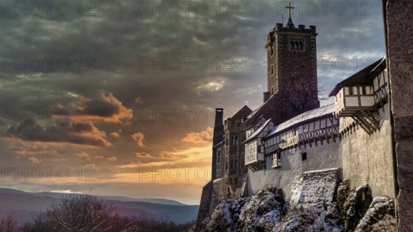 Snowy Wartburg in Eisenach in front of a picturesque and dramatic sky in romantic colors, at dusk, sunset, hiking on the Rennsteig, Thuringian Forest nature park Park