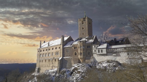 Snowy Wartburg in Eisenach in front of a picturesque and dramatic sky in romantic colors, at dusk, hiking on the Rennsteig, Thuringian Forest nature park Park