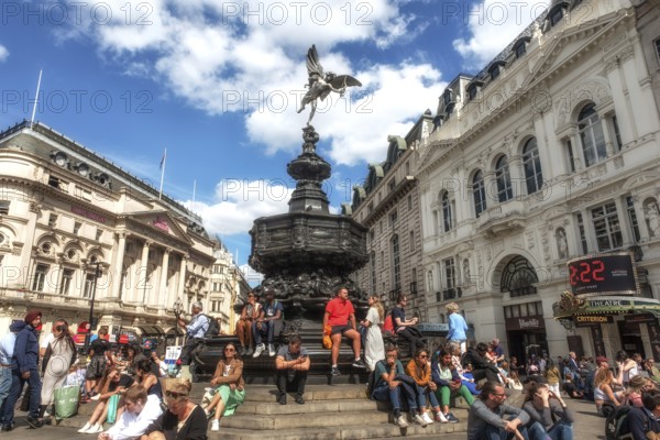London, United Kingdom, June 28th 2022 Tourists sitting on the steps of the Shaftesbury Memorial Fountain and statue of Greek god Anteros, Piccadilly Circus, London's West End