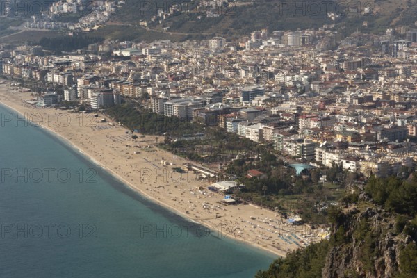 Aerial landscape view of houses and property in Alanya city set on the slopes the Taurus Mountains beside the beach and Mediterranean Sea, Turkey