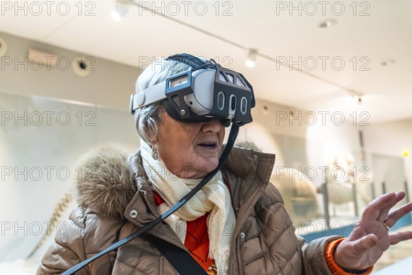 Senior woman wearing a vr headset, exploring immersive digital content and interactive exhibits in a modern museum style space, embracing technology and learning