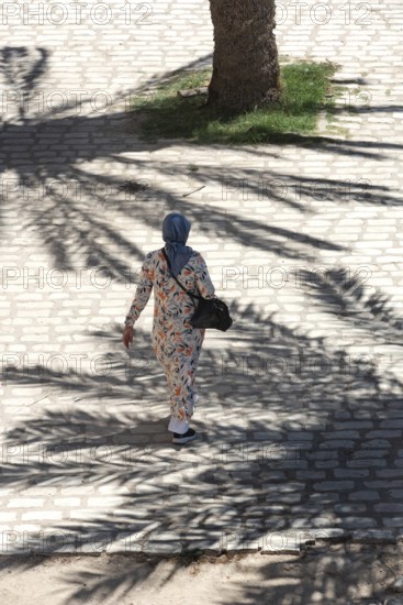 A Tunisian muslim wearing a patterned dress women walks in the streets of Sfax, the second largest city in Tunisia, North Africa
