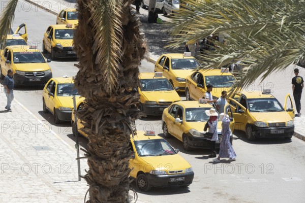 Streets of Sfax busy with taxi cabs waiting outside ancient fortified gate of Sfax Medina, known as Bab Diwan, Tunisia