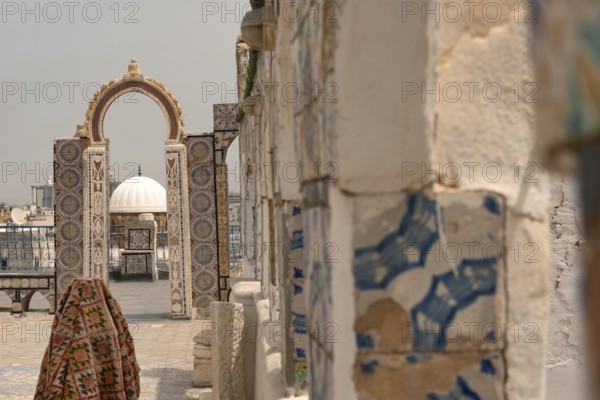 A rooftop view of a domed building through an archway decorated with traditional mosaic designs, part of the UNESCO designated Medina quarter of the Tunisian capital, Tunisia, North Africa