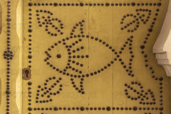 Distinctive fish design, an architectural detail of a traditional yellow painted door in the Medina of Tunis, a UNESCO designated quarter of the Tunisian capital, Tunisia