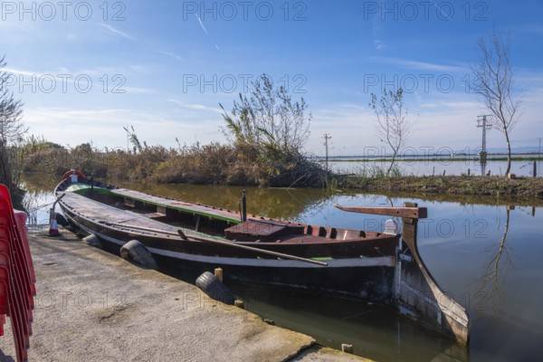 Traditional barca de l'albufera moored at a concrete pier in historic el palmar, reflecting valencias rustic lagoon culture within albufera natural park wetlands
