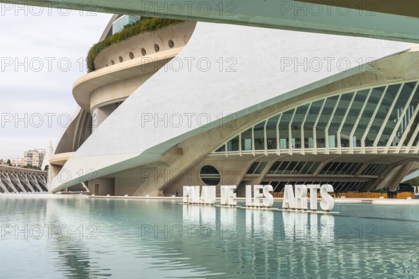 Palau de les arts reina sofia, an iconic architectural landmark by santiago calatrava, standing futuristically with its curved lines and glass facades, reflecting gracefully in the surrounding water