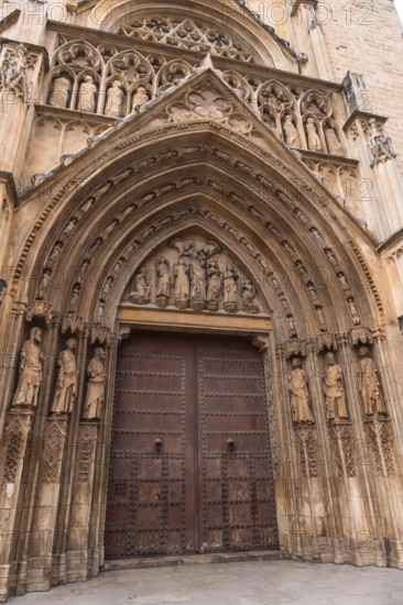 Valencia cathedral's door of the apostles displaying intricate gothic stone carvings. Religious sculptures and ornate portal reflecting medieval craftsmanship and spains historic spiritual heritage