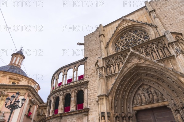 Valencia cathedral, a significant historic landmark, showcasing the ornate gothic architecture of the apostles door, rose window, and traditional elements against a cloudy sky in spain