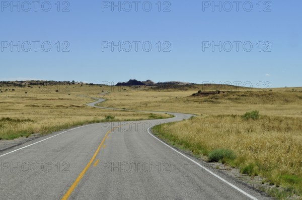 Endless road snakes through a dry desert landscape under a clear blue sky, Canyonlands National Park, Island in the Sky, Utah, USA