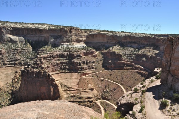Majestic views of rugged canyons and deep gorges into which a narrow gravel road leads, under blue skies, Canyonlands National Park, Island in the Sky, Utah, USA