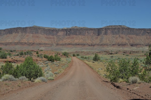 Straight gravel road through a flat, wide desert landscape, Canyonlands National Park, Island in the Sky, Utah, USA