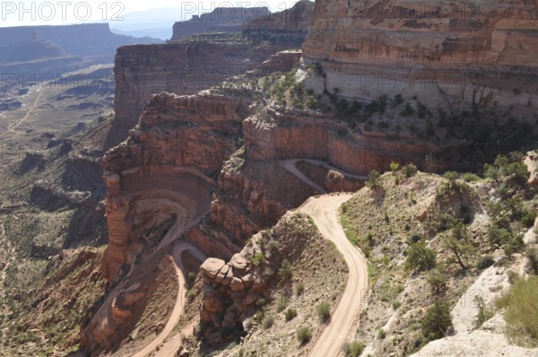 Narrow gravel road winds along steep rocks in a canyon landscape, Canyonlands National Park, Island in the Sky, Utah, USA