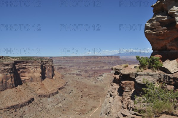 Rock cliffs with spectacular views of the vast, dry desert landscape and a narrow gravel road, Canyonlands National Park, Island in the Sky, Utah, USA