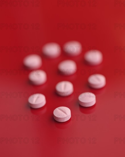 A striking image featuring several pink tablets casually dispersed on a saturated red backdrop, highlighting both contrast and detail perfect for medical and health-related themes
