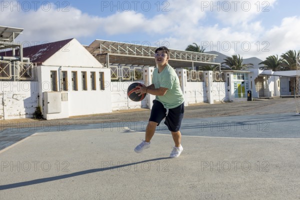 A Down syndrome teenager actively participates in a lively basketball game, This heartwarming scene captures the joy and inclusion in family sports activities
