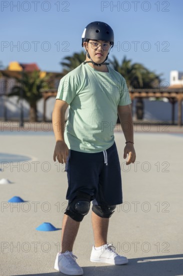 Teenage boy with Down syndrome enjoying outdoor sports activities, wearing safety equipment