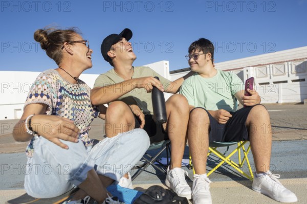 Down syndrome teenager sits with family members, sharing laughter and joy during an outdoor sports day A moment capturing inclusion and family bonding through sports activities