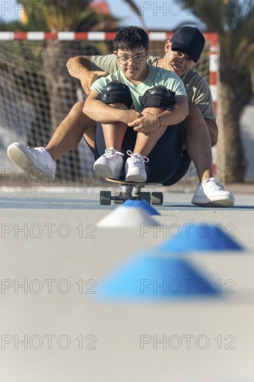 A teenager with Down syndrome enjoys a sporting activity with his brother, riding a skateboard outdoors The moment shows joy, inclusion and active participation in leisure activities