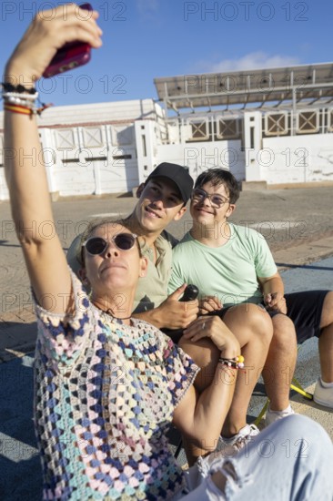 A heartwarming family moment as a teenager with Down Syndrome poses for a selfie with loved ones outdoors The sunny setting highlights joy, togetherness, and inclusivity