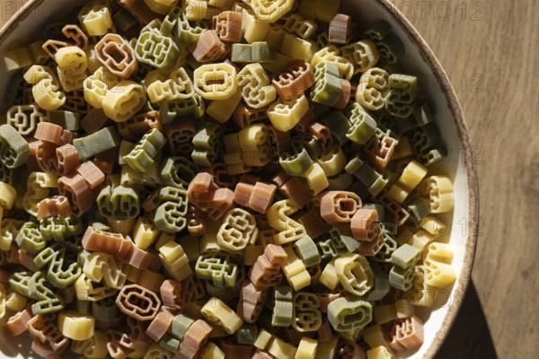 A bowl filled with multi-colored number shaped pasta featuring various digits. The numbers are not clear enough to identify any specific year