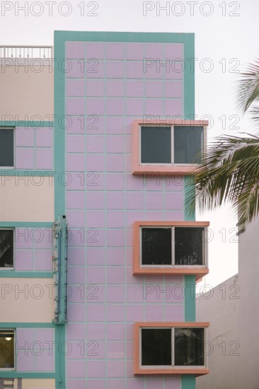 Vibrant image showing a Miami Beach Art Deco building with pastel pink and turquoise colors juxtaposed against bold window frames, capturing the distinctive architectural style topped with a serene sky background