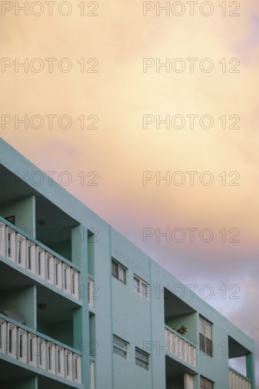 Soft sunset colors bathe a Miami Beach building, rendering the sky in warm peach tones above the cool mint green structure
